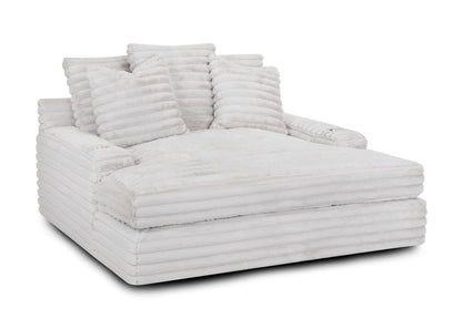 The Oasis Snuggle Chaise, a spacious white ribbed lounge, is adorned with several matching pillows.