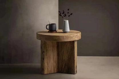 Antique Round Wood Tea Table adorned with a black mug and a gray vase holding dried flowers, set against a minimalist background.