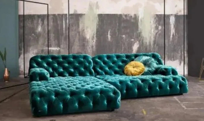 Coco Miralda Sofa in teal, accented with a yellow throw pillow, situated in an industrial-style room featuring a partially unfinished wall.