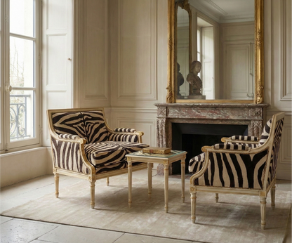 Two zebra-patterned chairs in a room with a fireplace and large mirror.