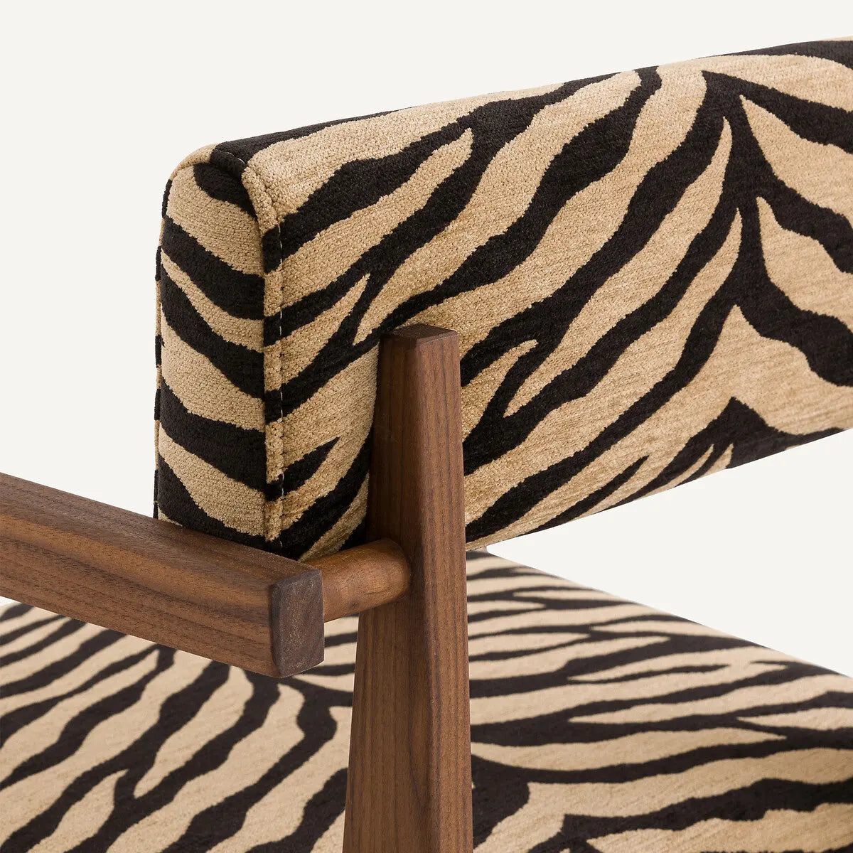 Close-up of the Savannah Stripes Dining Chair, showcasing zebra-print fabric on the backrest and seat. The chair features a wooden frame with simple, clean lines.