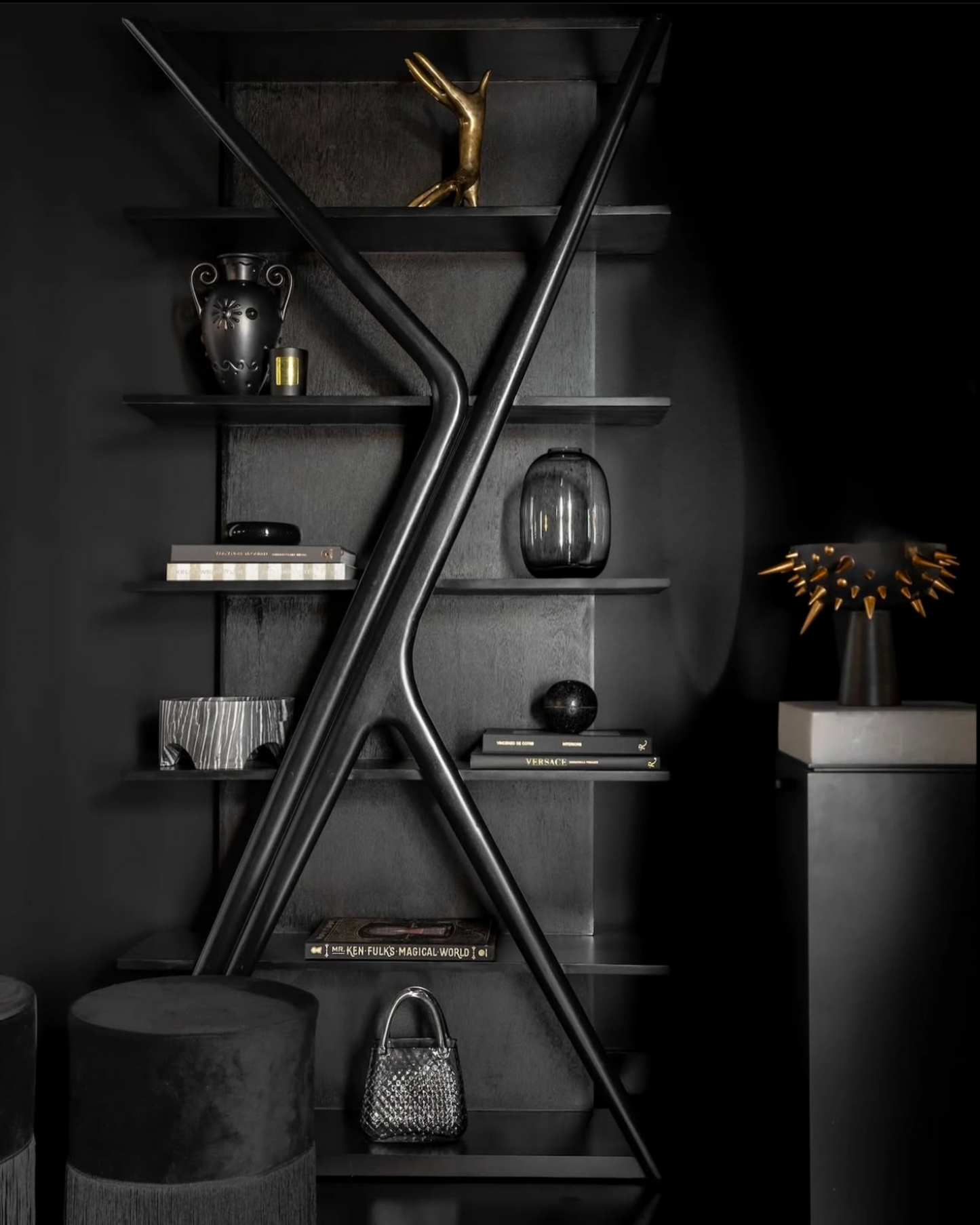 Modern black metal shelf with decorative items against a dark background